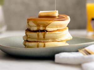 Stack of Japanese Souffle Pancakes on a Plate Topped with Butter and Maple Syrup
