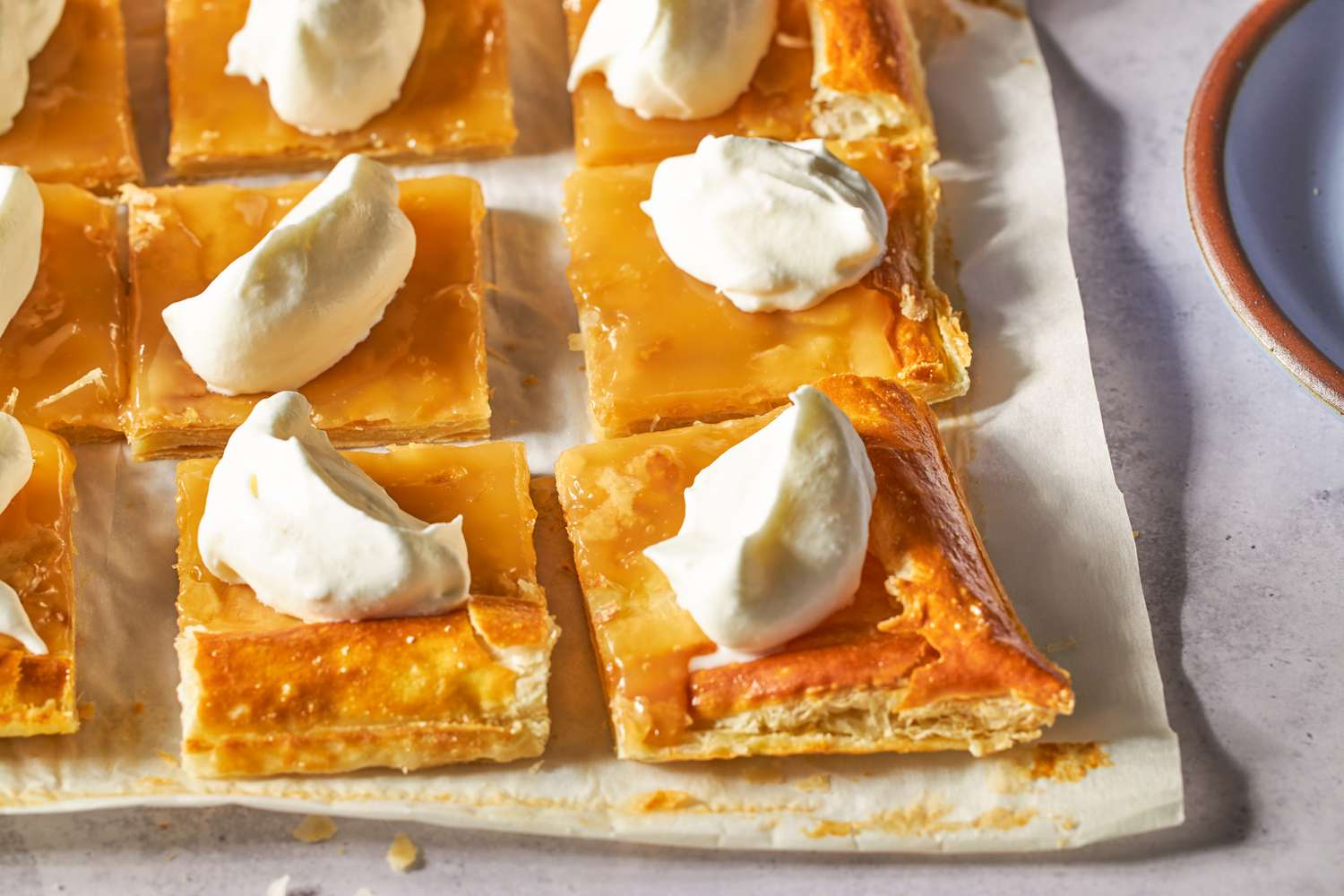 Lemon curd tarts topped with whipped cream, arranged in square portions.