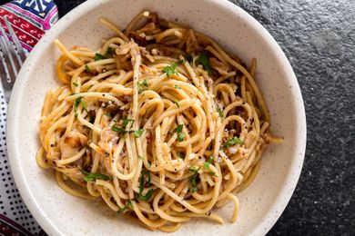 A white bowl with caramelized cabbage spaghetti, garnished with chopped parsley