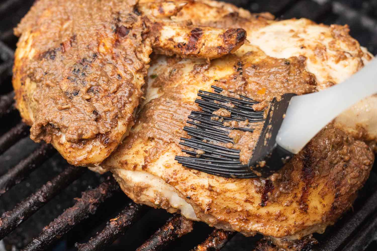 Basting chicken to make a jerk chicken recipe.