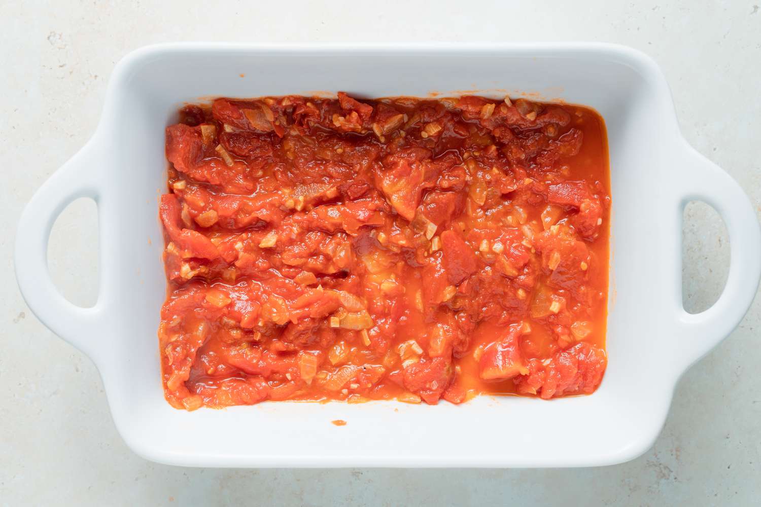 Sauce spread at the bottom of a casserole dish to make chili relleno casserole.