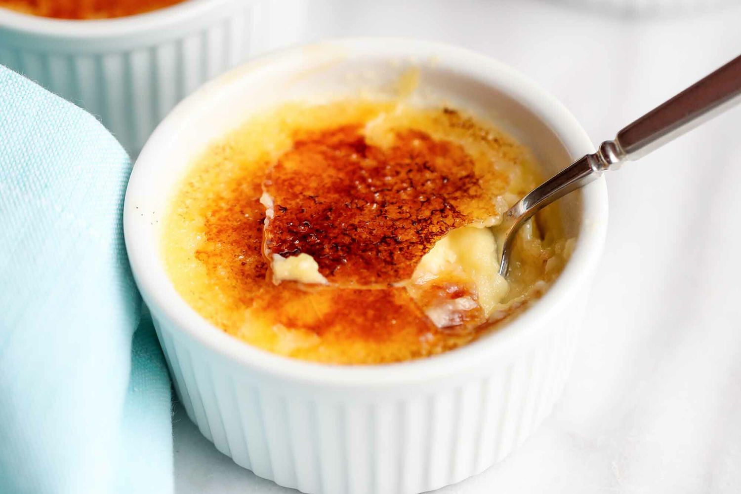 A Creme Brulee with a spoon dipping in to pull out a bite