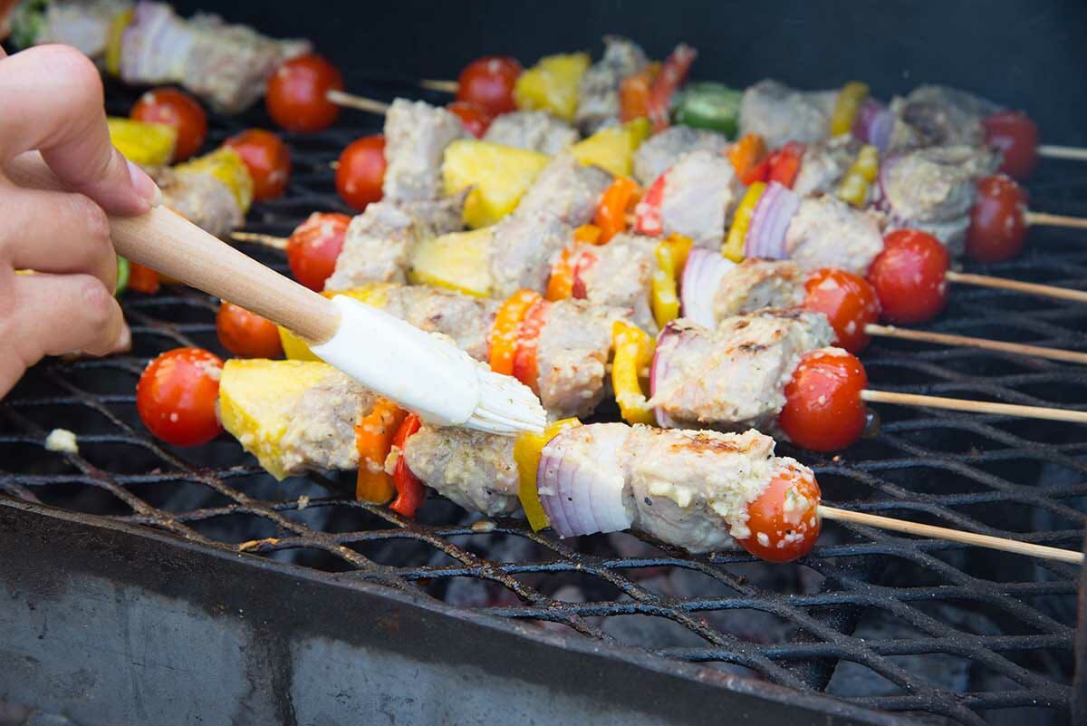 Pork kebabs with mojo marinade on the grill and being brushed with mojo marinade.