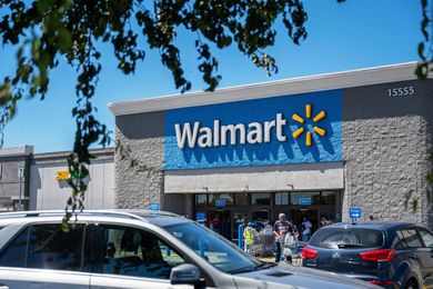 Exterior of a Walmart store with parked cars and some customers near the entrance