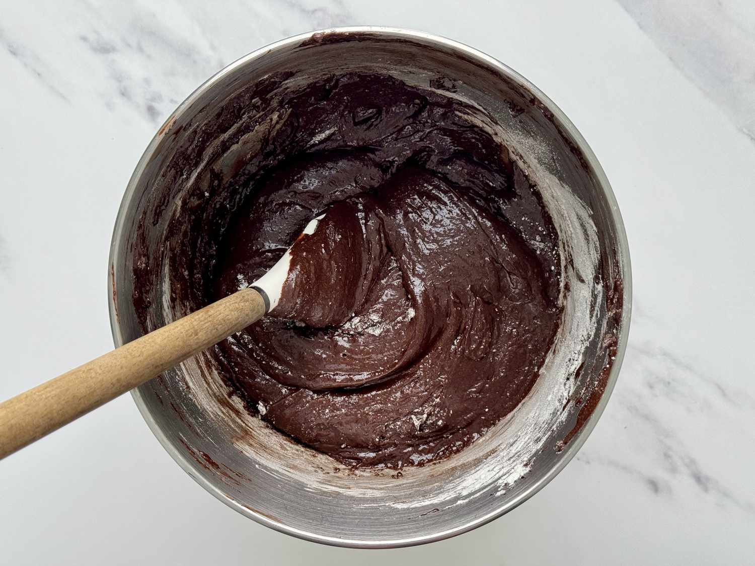 Overhead shot of the brownie batter in a mixing bowl with a silicone spatula sticking out