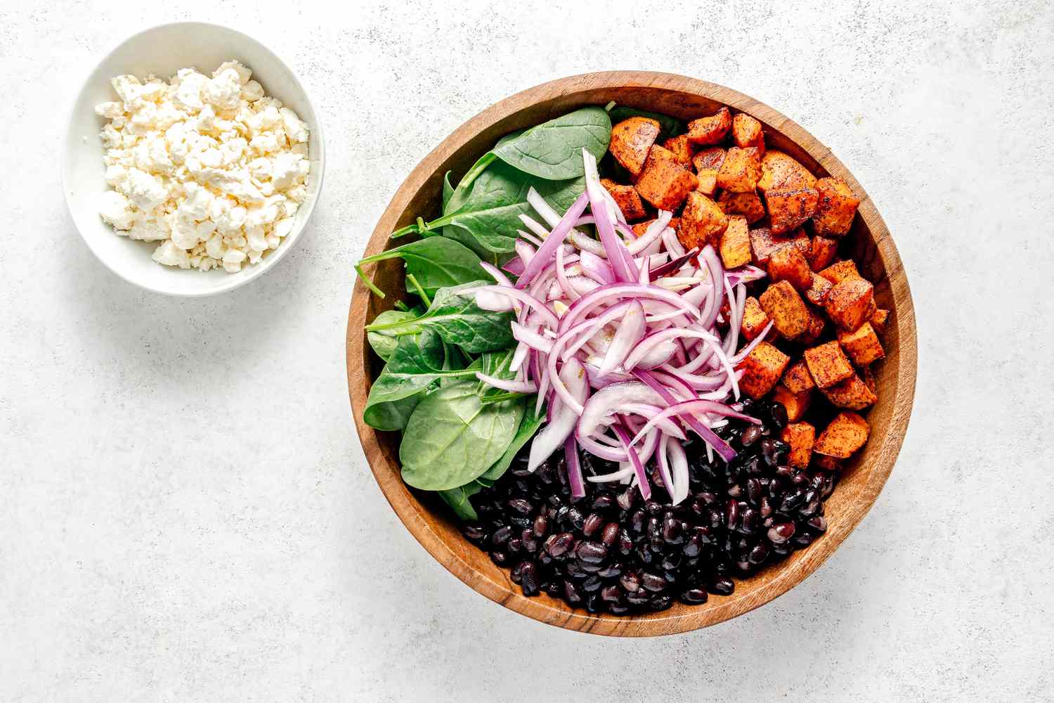 Roasted Sweet Potato Salad Ingredients Neatly Organized in a Bowl with a Bowl of Crumbled Feta Cheese Next to It