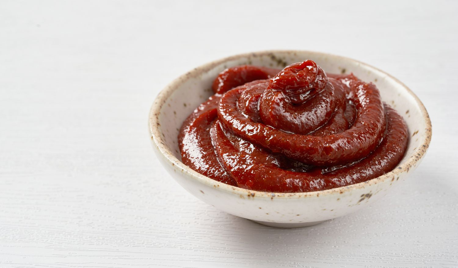 Bright red gochujang in a small ceramic bowl