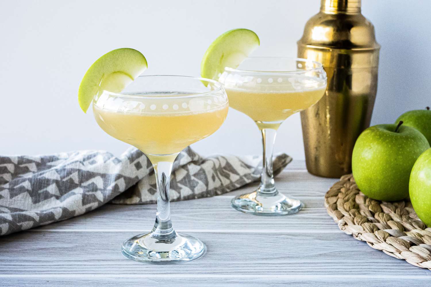 Two easy appletini cocktails and gold cocktail shaker.