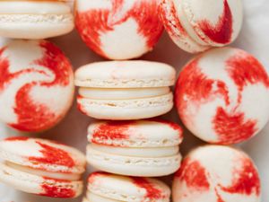 Overhead view of peppermint macarons with white chocolate filling on a baking sheet.