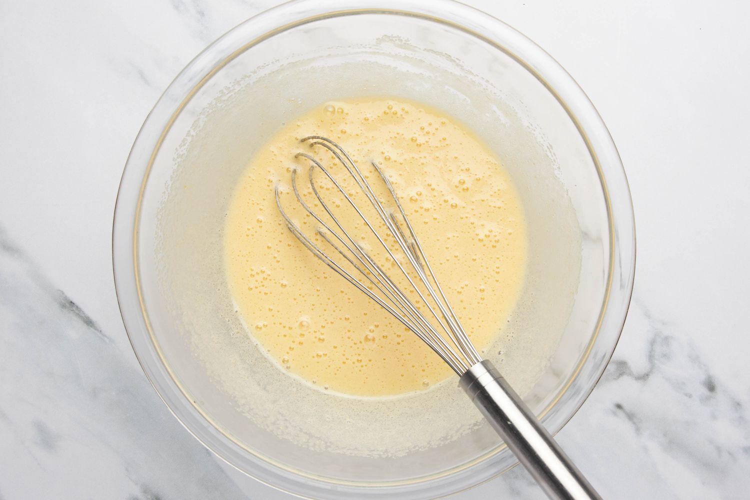 Egg, sugar, and vanilla extract whisked together in a bowl for lazy daisy cake recipe 