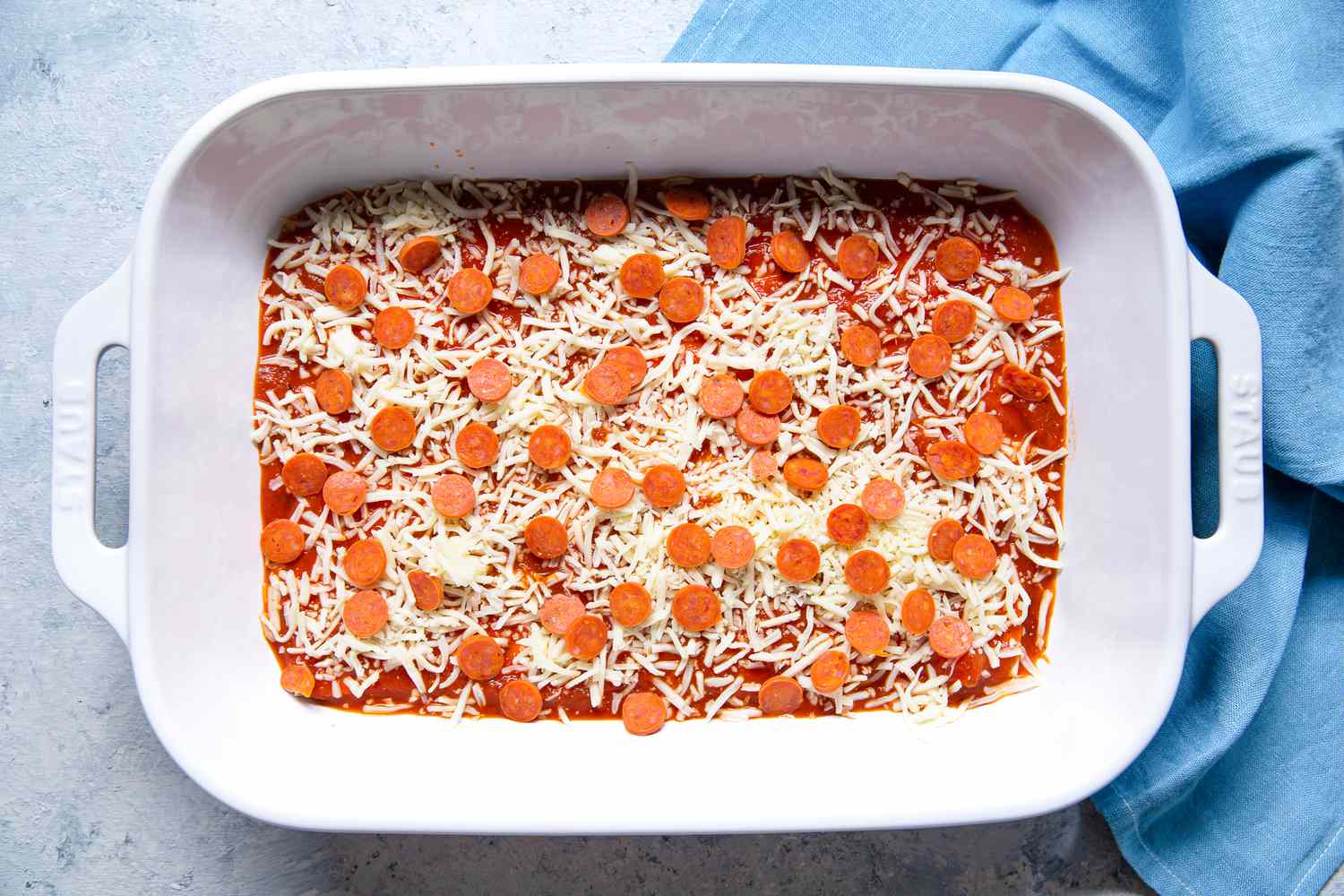 Mini Pepperoni Slices Added to Casserole Dish for Pepperoni Pizza Lasagna Recipe