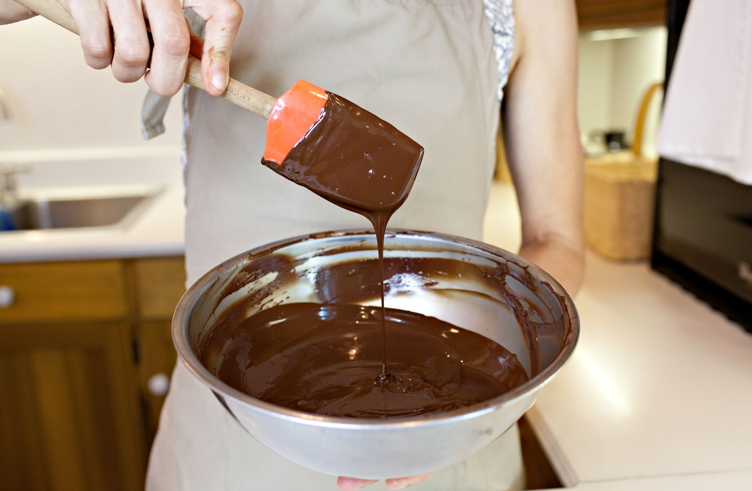 Chocolate Dripping Off the Side of a Spatula into a Bowl with More Melted Chocolate for How to Temper Chocolate