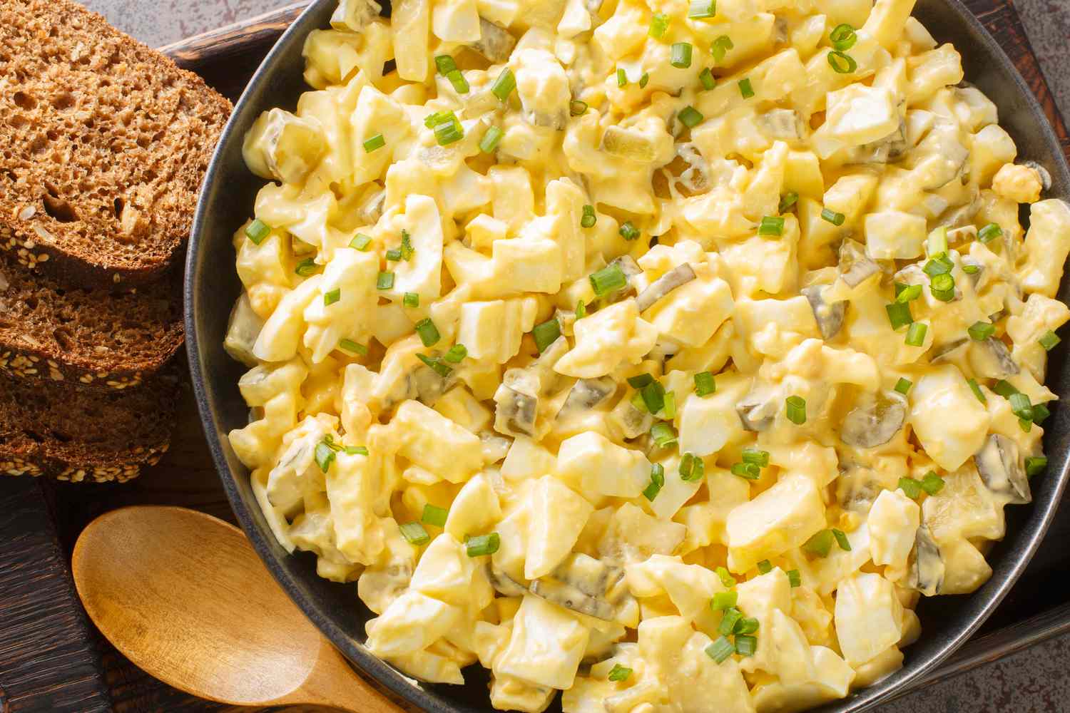 Egg salad in a bowl next to bread slices