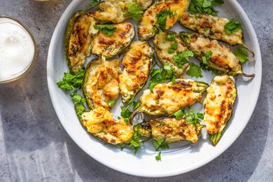 Baked stuffed jalapeños on white plates with glasses of beer