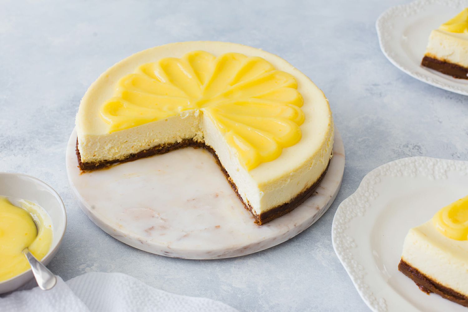 Lemon Cheesecake on a marble platter with 1/4 of the slices removed