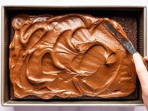 Overhead view of spreading the whipped ganache on the cooled cake for Easy Brooklyn Blackout Cake recipe