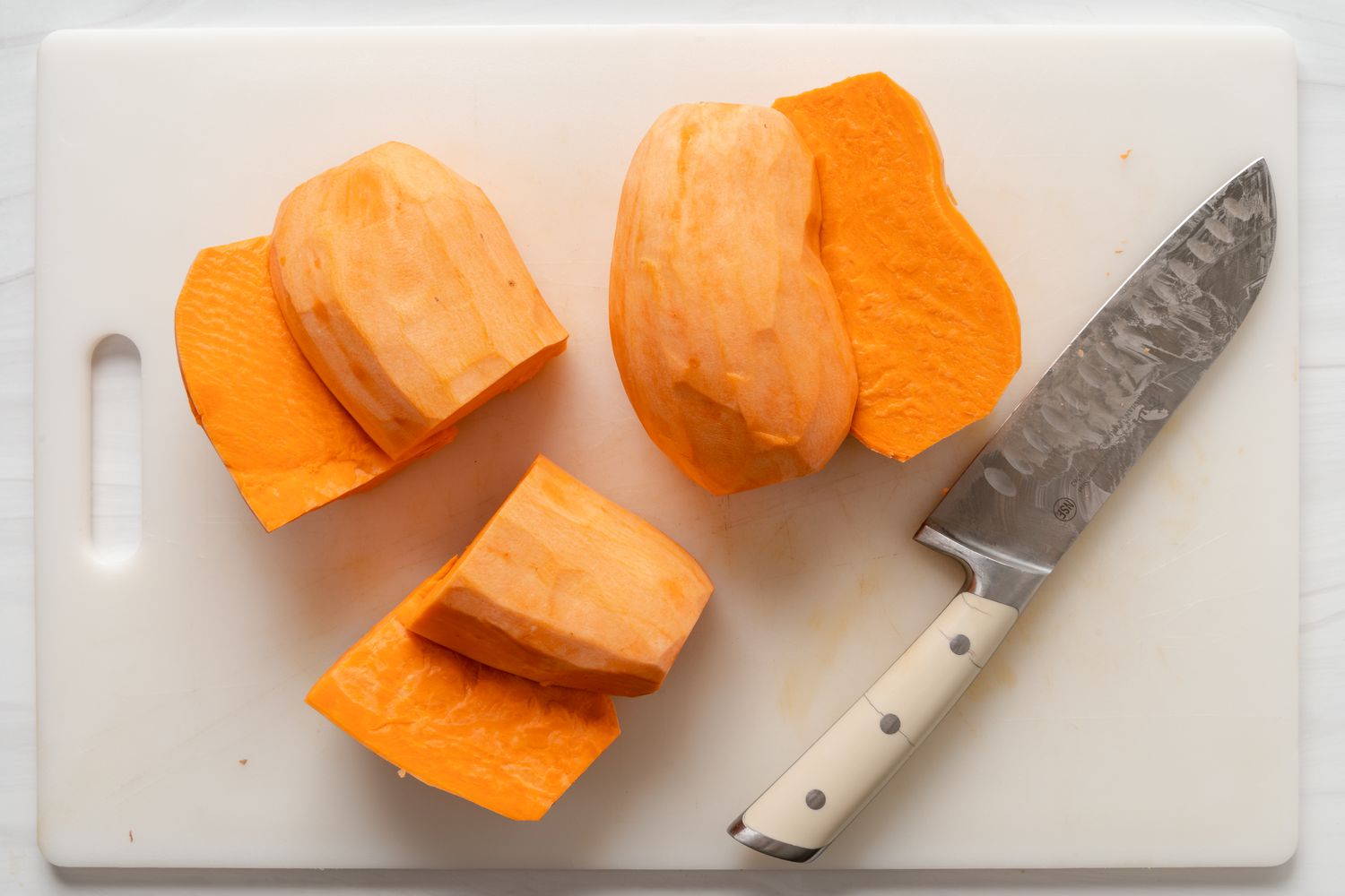 Sweet potatoes peeled and halved on a cutting board
