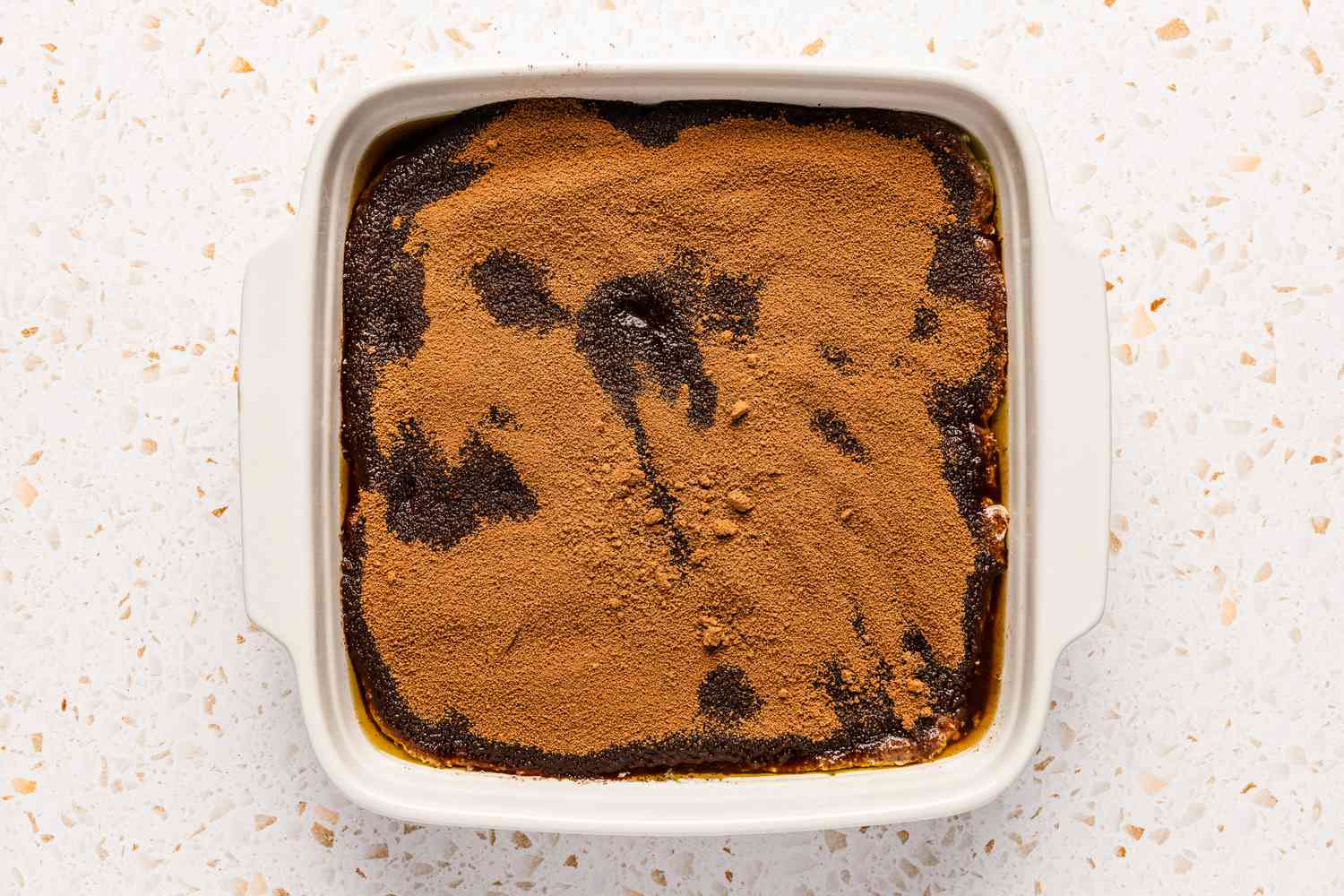 Brown sugar mixture sprinkled on top of the batter in the square baking dish for chocolate cobbler recipe