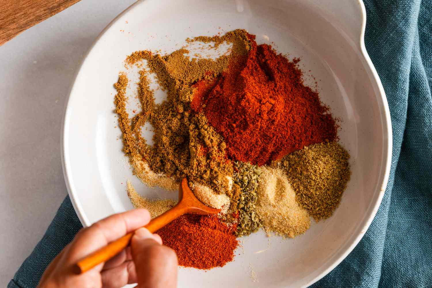 Spices being mixed together in a bowl to make homemade chili powder 