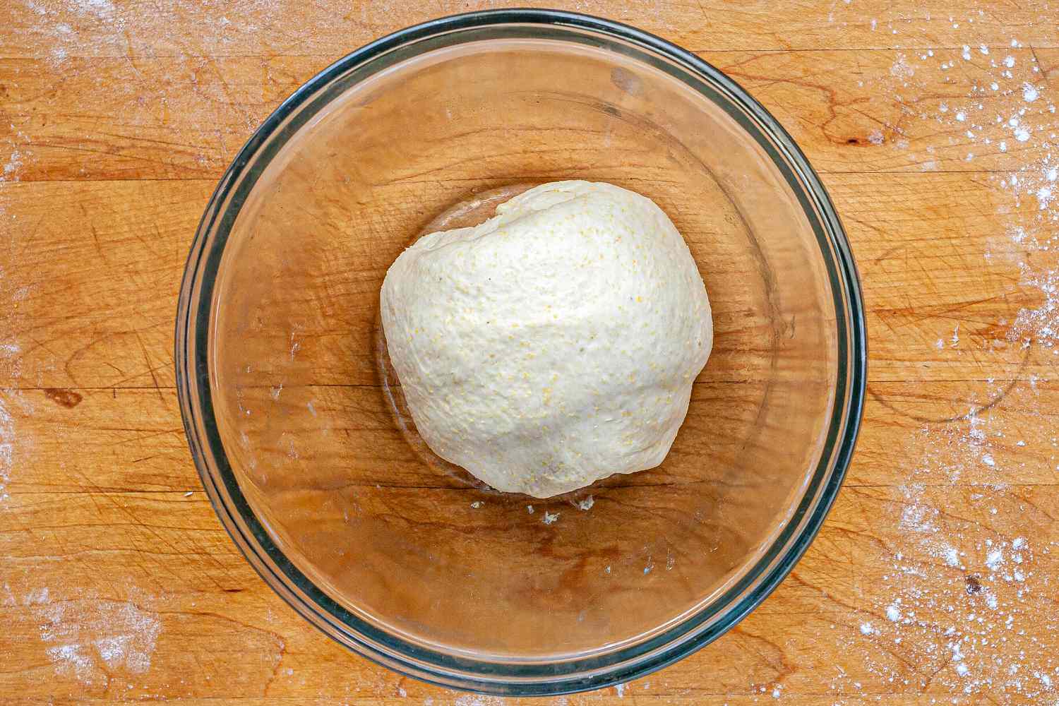Dough in a glass bowl to make Italian Sausage Deep Dish Pizza.