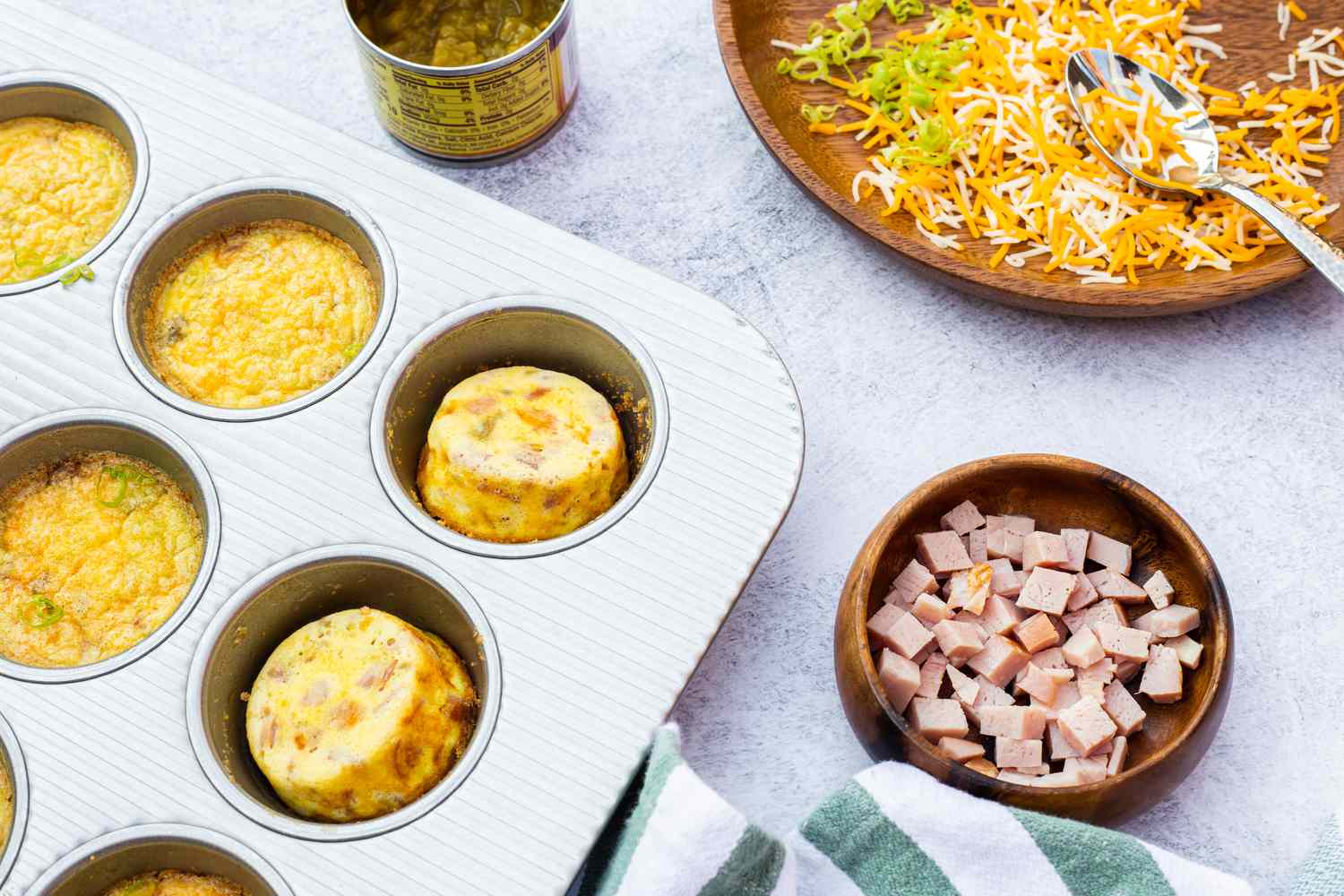 Ham, Cheddar, and GreenaHam, Cheddar, and Green Chile Egg Bites in a Muffin Tin Next to Bowls of Ingredients Chile Egg Bites on a Plate