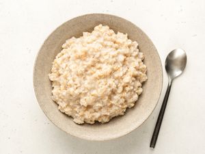 A bowl containing oatmeal accompanied by a spoon