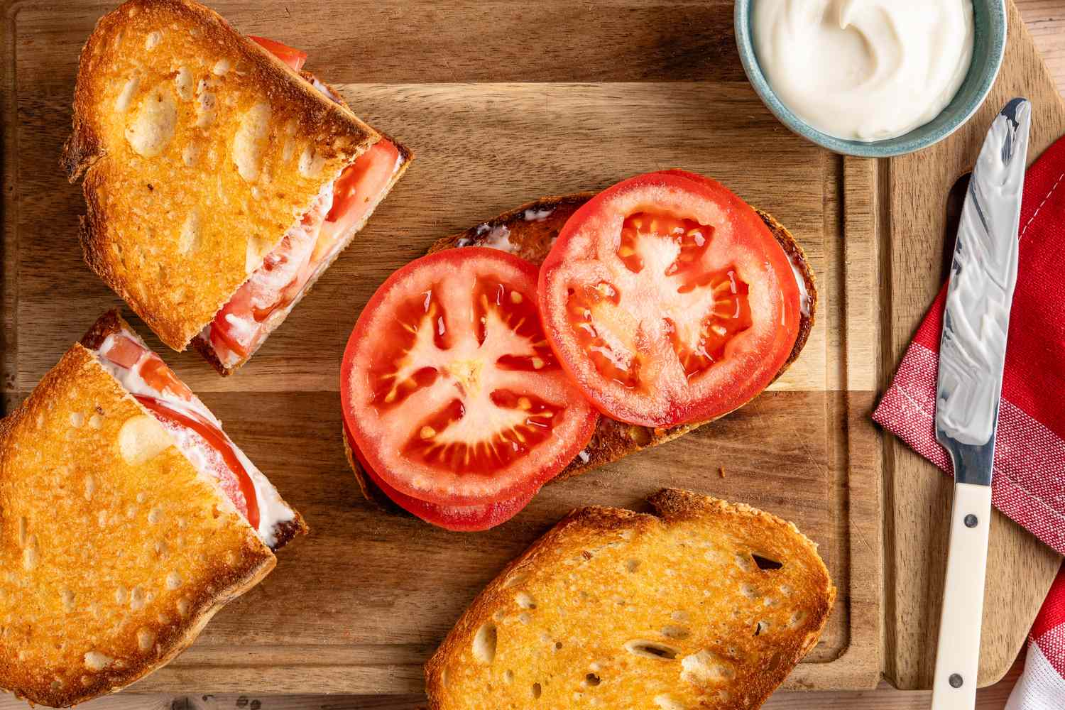 Open tomato sandwich with a side of mayonnaise on a wooden board