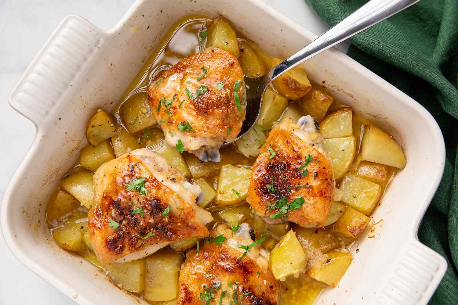 Garlic butter chicken thighs with potatoes in a baking dish