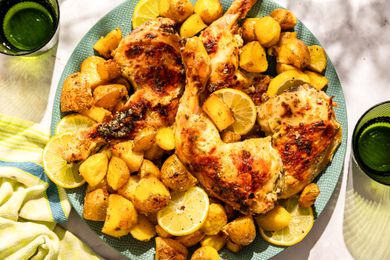 A large plate of Greek-style roast chicken with potaotes and lemon slices