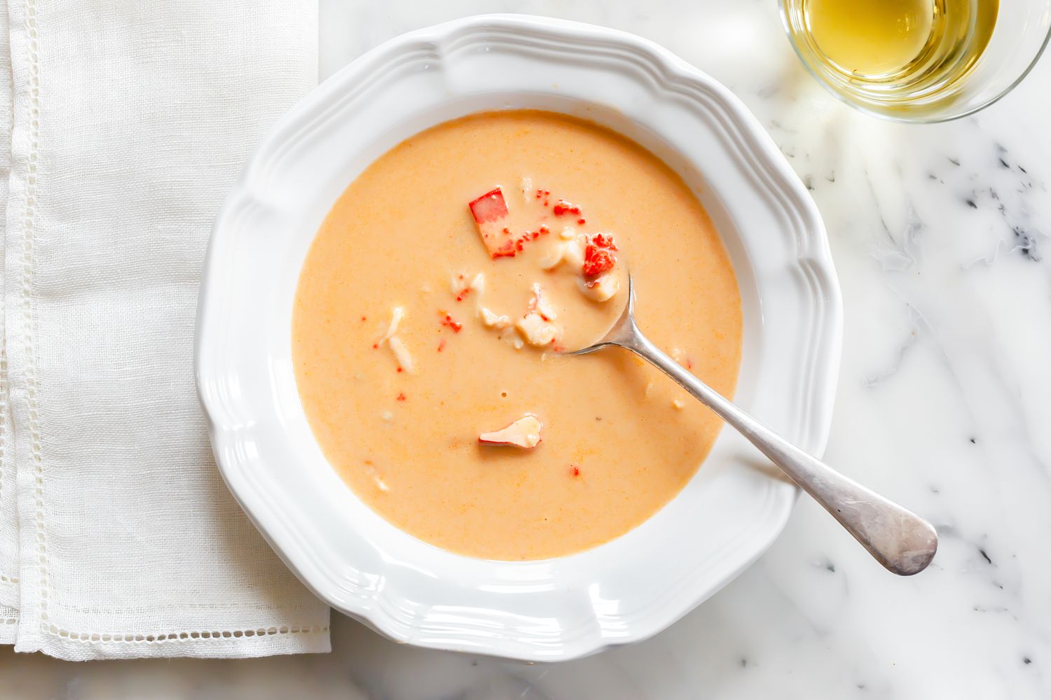 Bowl of Lobster Bisque with a Spoon Next to a Table Napkin and a Glass