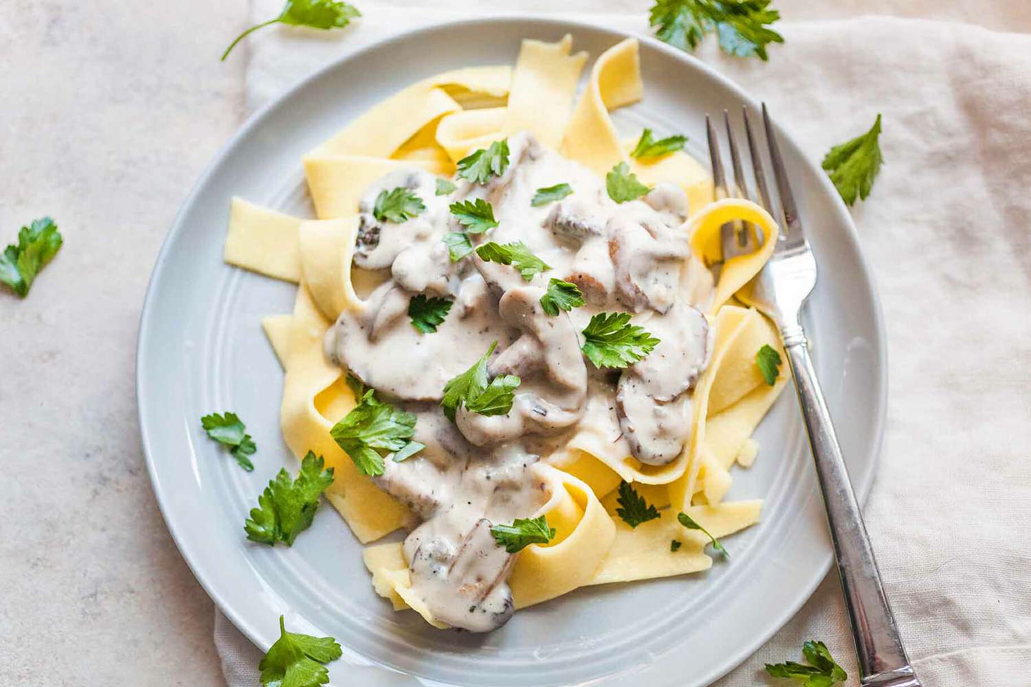 A plate of fettucine alfredo with mushrooms and parsley, ready to serve.