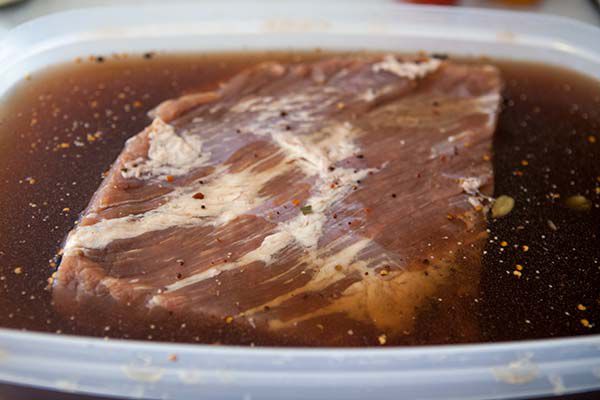 A cut of beef resting in a marinade sauce 