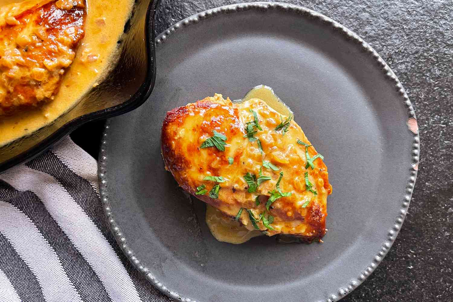 Overhead view of a black plate with a chicken breast of Ina Garten's Chicken With Shallots recipe