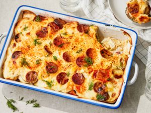 Rakott Krumpli (Hungarian Potato Casserole) in a 9x13 casserole dish, one serving on a plate
