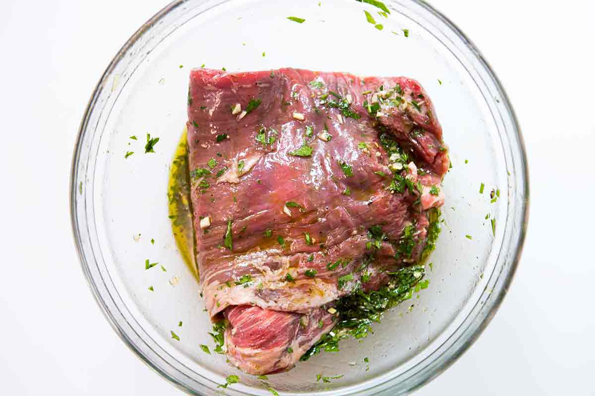 flank steak in glass bowl with marinade
