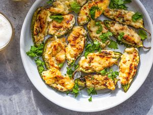 Baked stuffed jalapeños on white plates with glasses of beer