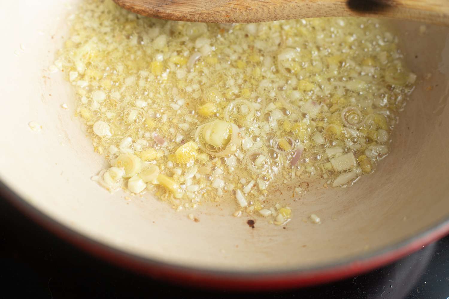 Sauteeing aromatics for a fish poached in coconut with ginger and lime recipe.