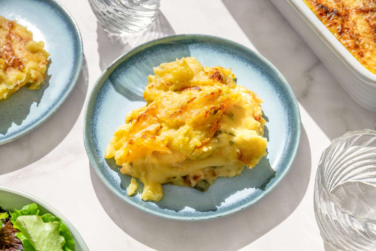 A serving of Irish baked mashed potatoes on a blue plate, on a white marble counter