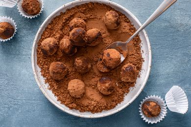 Truffles rolled in cocoa powder on a plate with a spoon