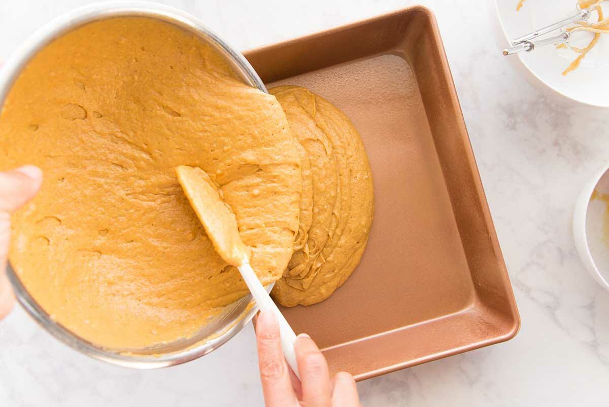 Batter for The Best Pumpkin Cake with Cream Cheese Frosting being poured into a cake pan.