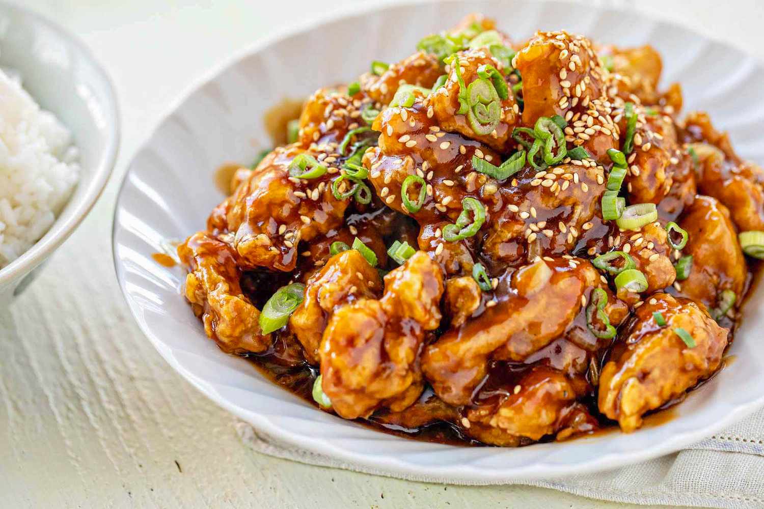 Bowl of Chinese Orange Chicken Next to a Bowl of Rice 
