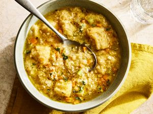 A bowl of pancotto soup with bread pieces and vegetables served with a yellow napkin