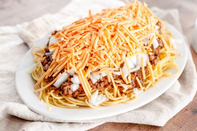 Vegan Cincinnati Chili Served over a Platter of Pasta and Topped with Cheese and Onions
