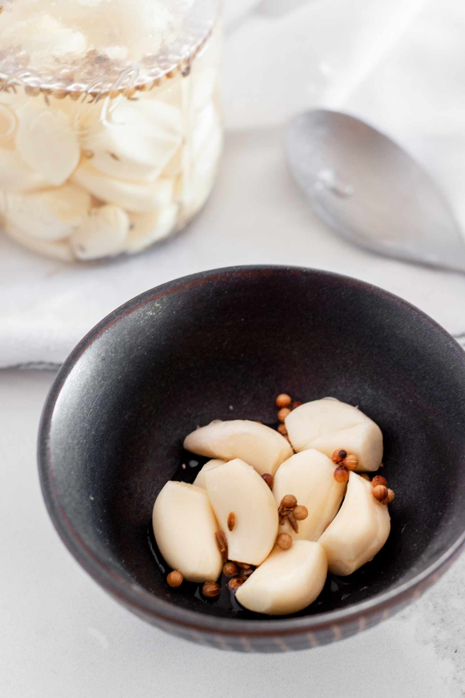 Pickled Garlic in a Bowl with More in the Jar in the Background