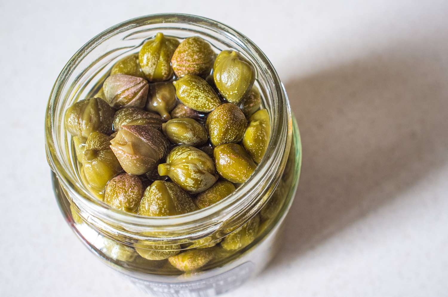 A close up shot of an open jar of capers