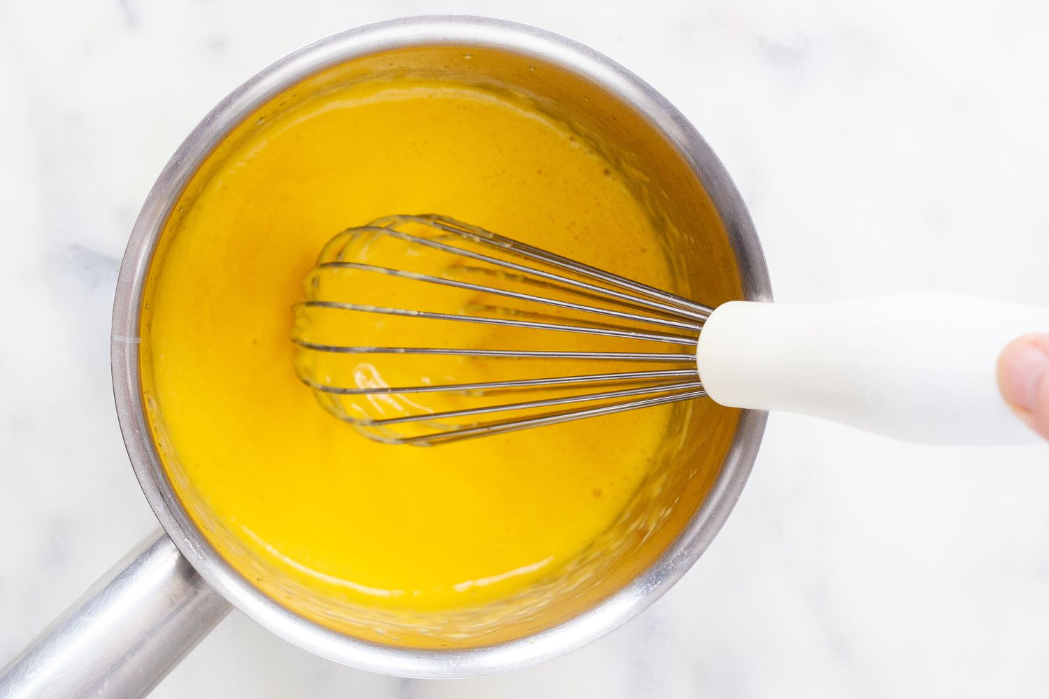 A saucepan with whisked egg yolks inside to make béarnaise sauce.