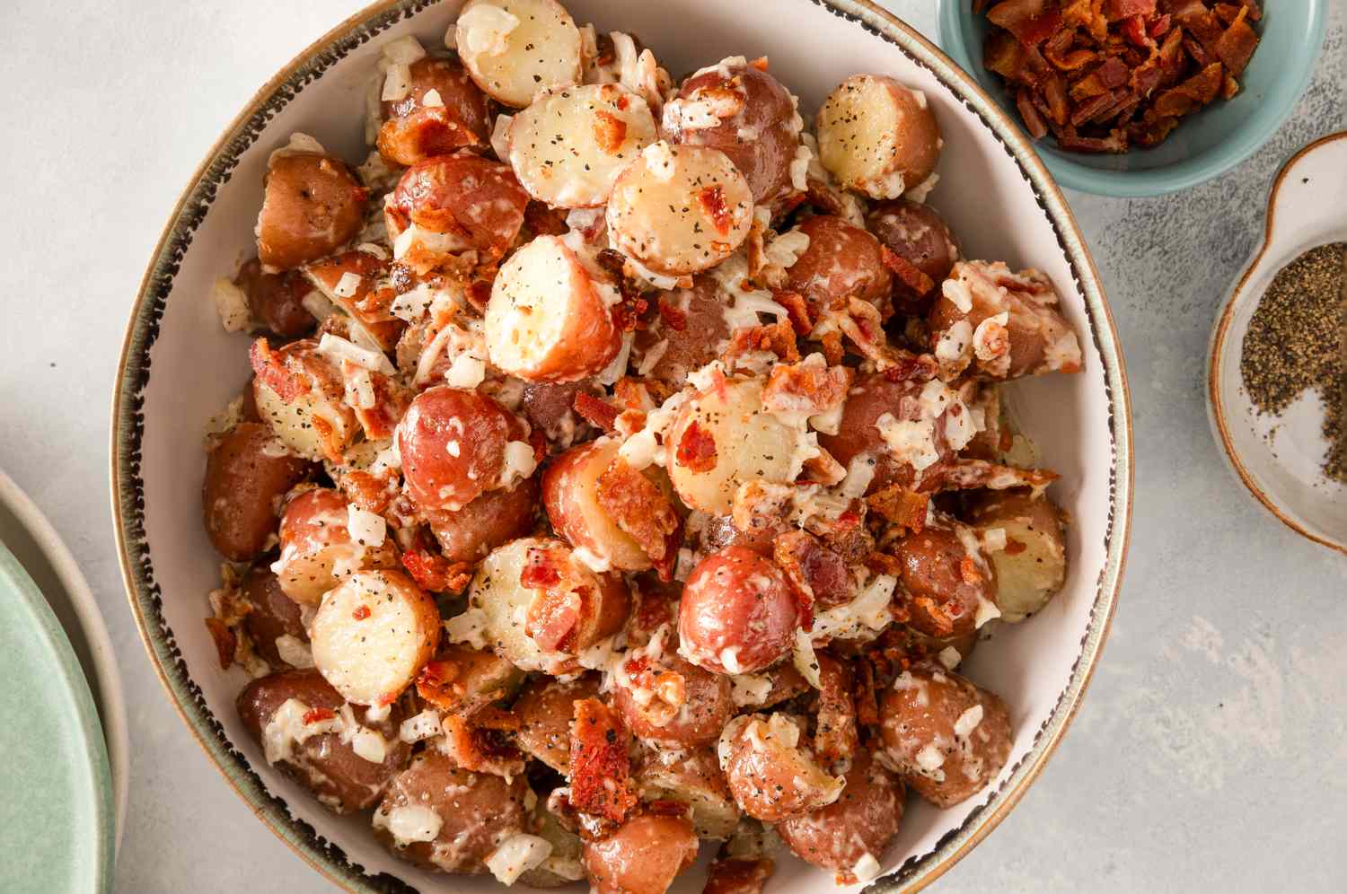 A bowl of potato salad topped with crumbled bacon