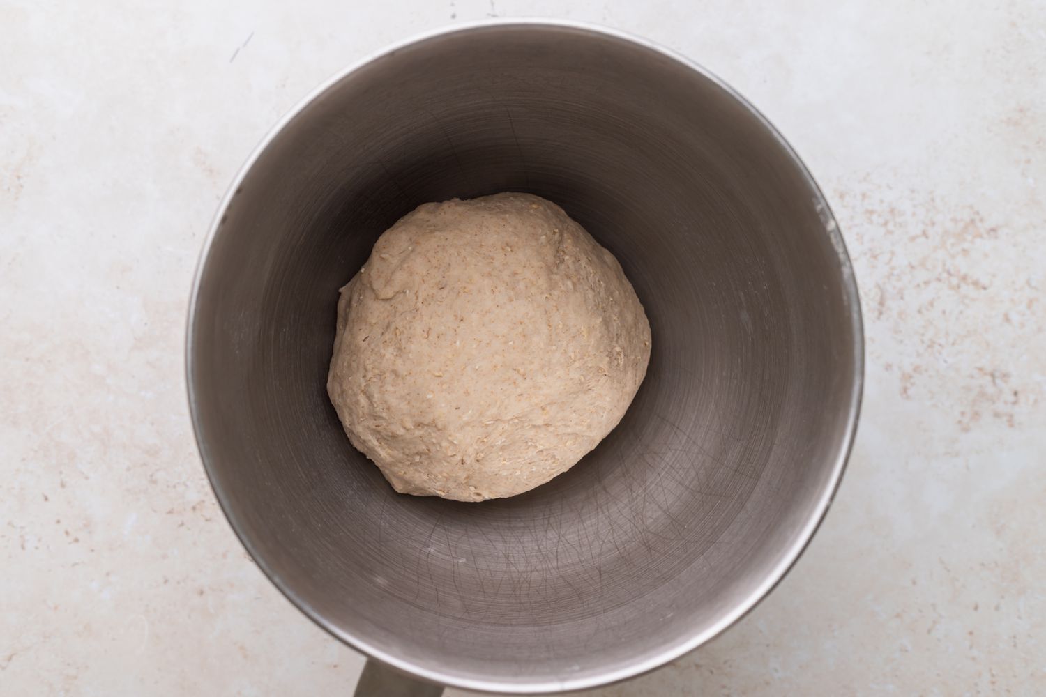 Dough for oat bread rising in a bowl to show how to make oatmeal bread.