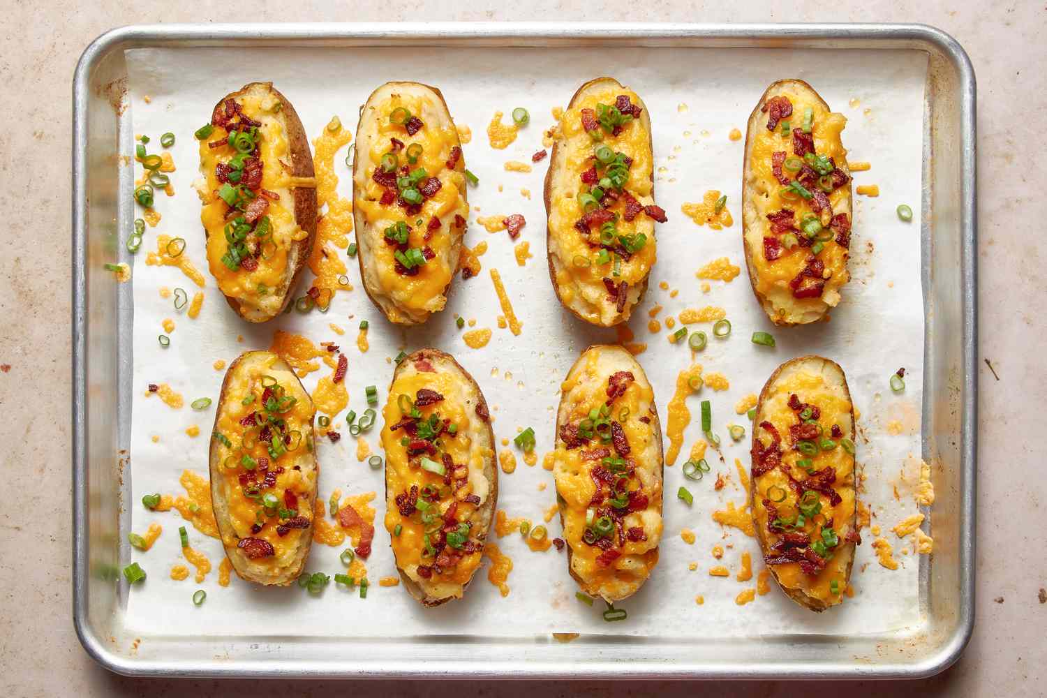 Twice baked potatoes topped with spring onions and bacon bits (still on the baking sheet)