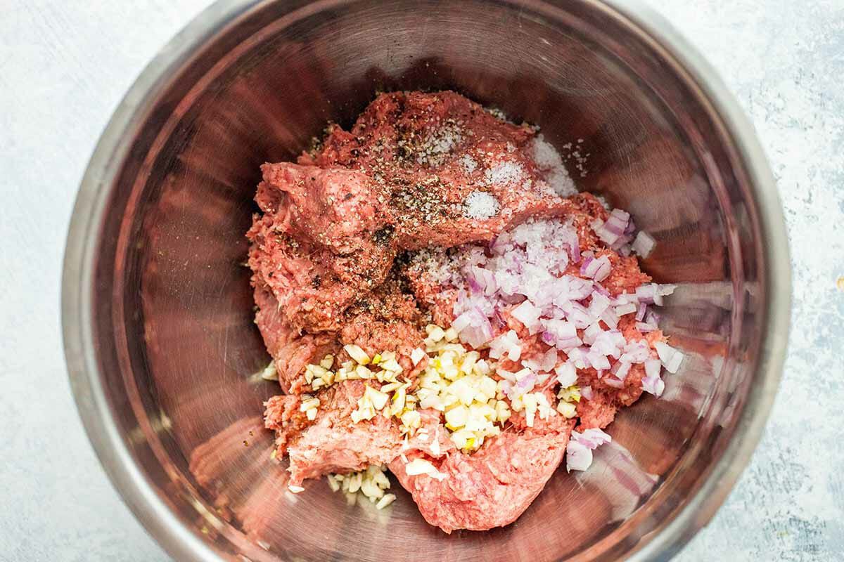 A bowl of ground beef, garlic, onions, Worcestershire sauce, ground pepper, and salt